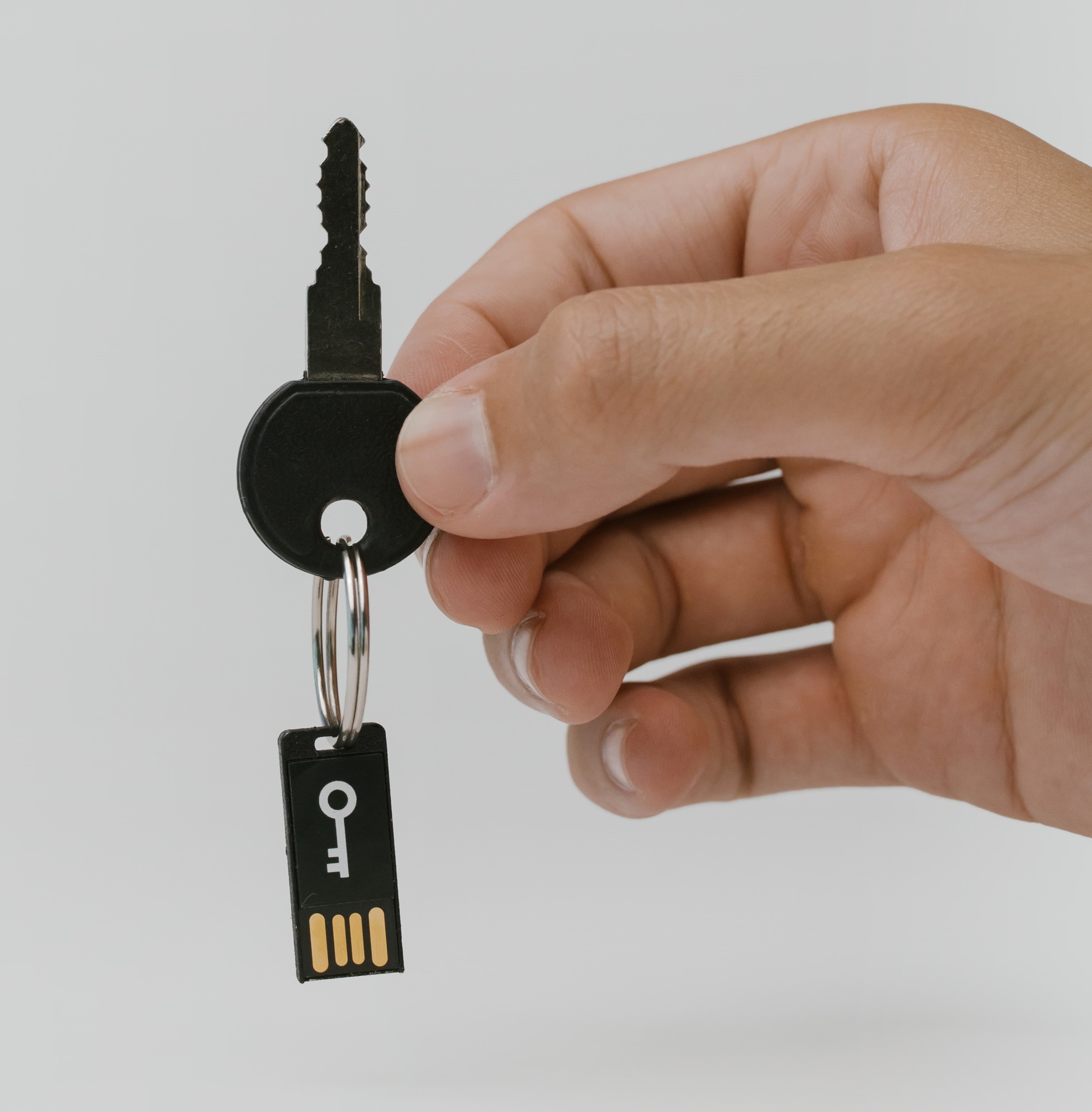 يد تمسك بمفتاح حقيقي بحلقة مفاتيح متصلة بجهاز مصادقة ثنائي العوامل